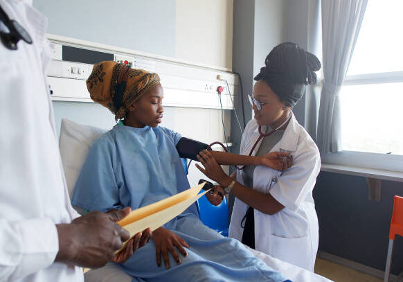 istockphoto-1085676456-612x612 An African young Female Doctor taking blood pressure on a young patient with a headscarf Cape Town South Africa